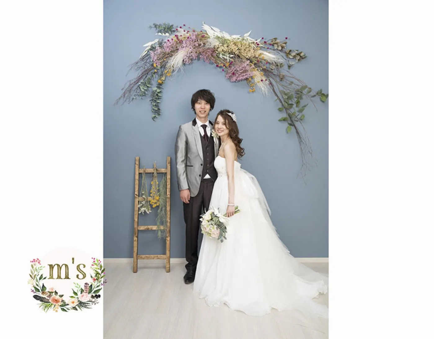 花のアーチを背景にした、ウェディングドレスとタキシードのスタジオ撮影
