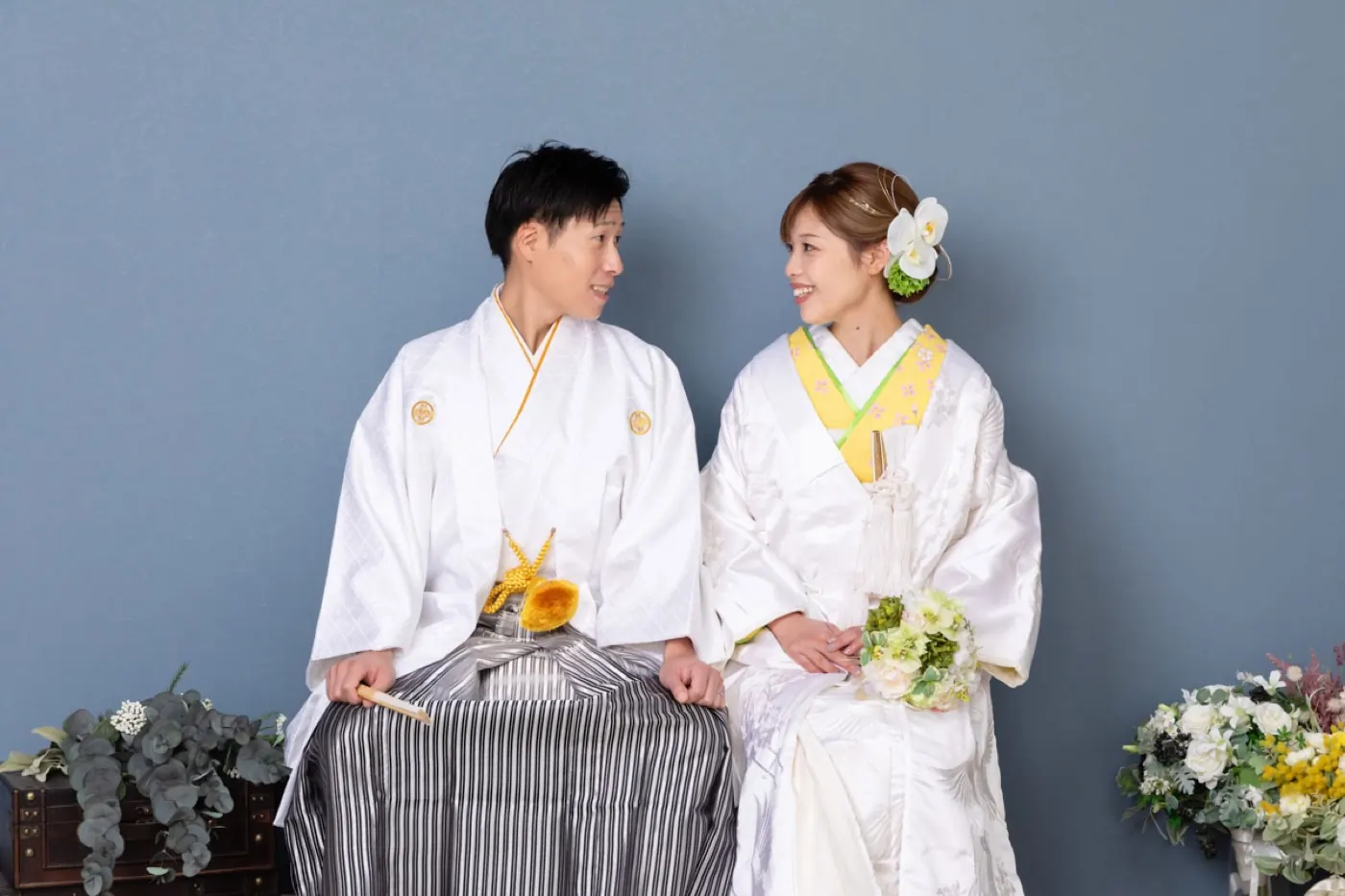 淡い色合いの色打掛を着た花嫁と、和装の花婿のスタジオ撮影
