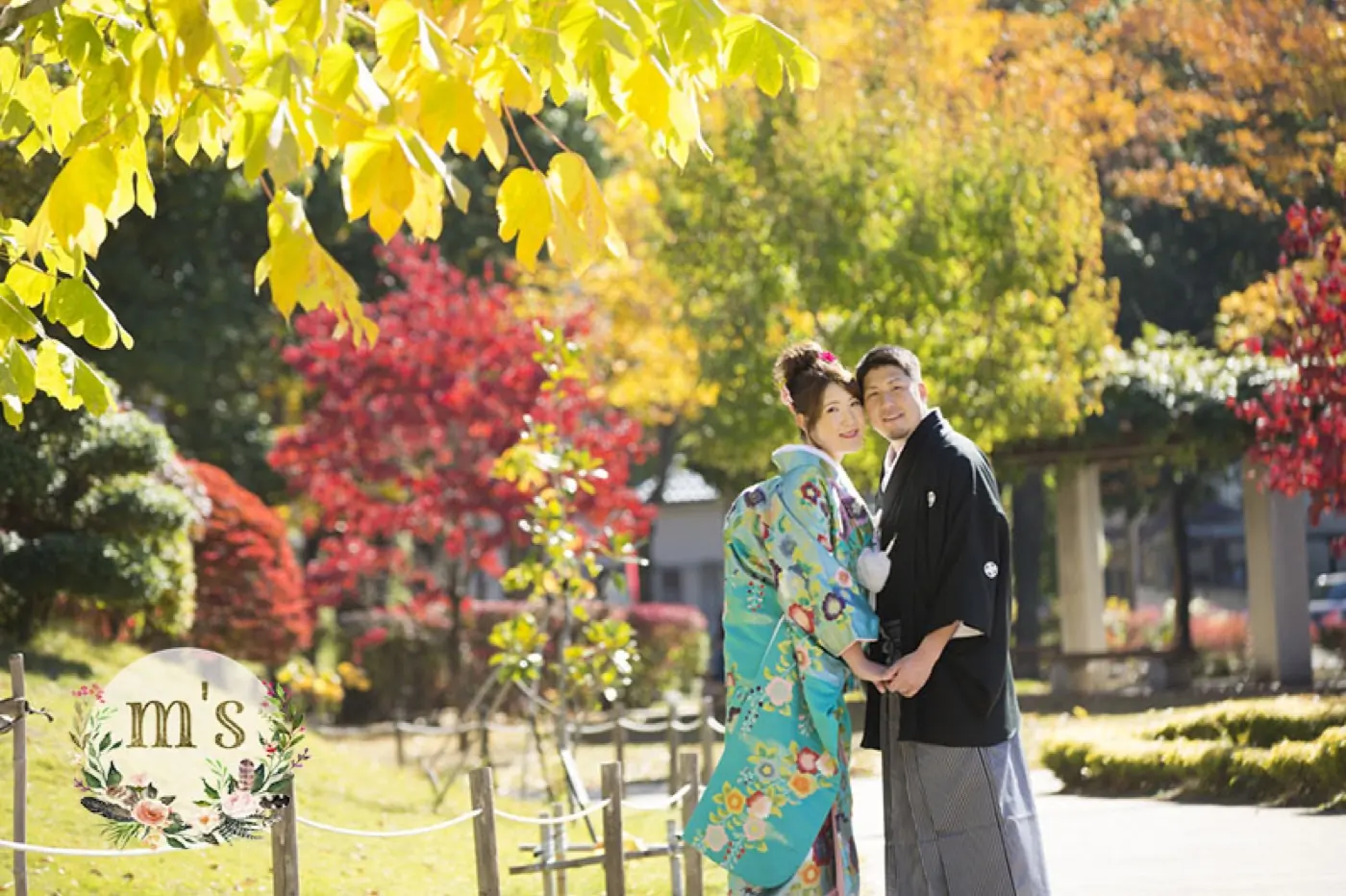 紅葉の中に立つ、鮮やかな色打掛の花嫁と紋付袴の花婿