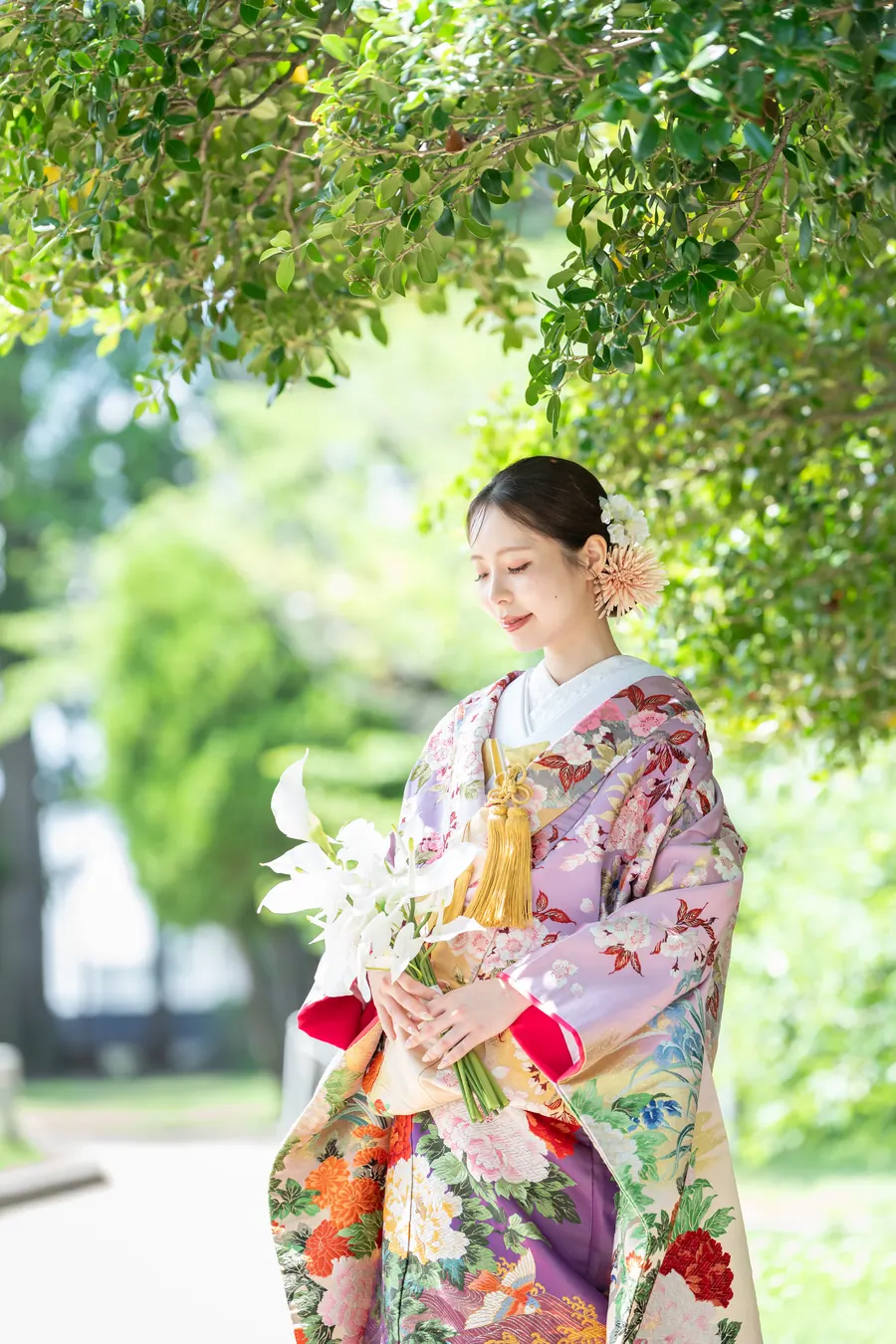 百合の和装ブーケを持ち、木漏れ日の下に立つ色打掛の花嫁